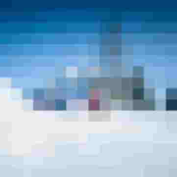 Familie rodelt im Schnee vor verschneitem Bergpanorama und blauem Himmel